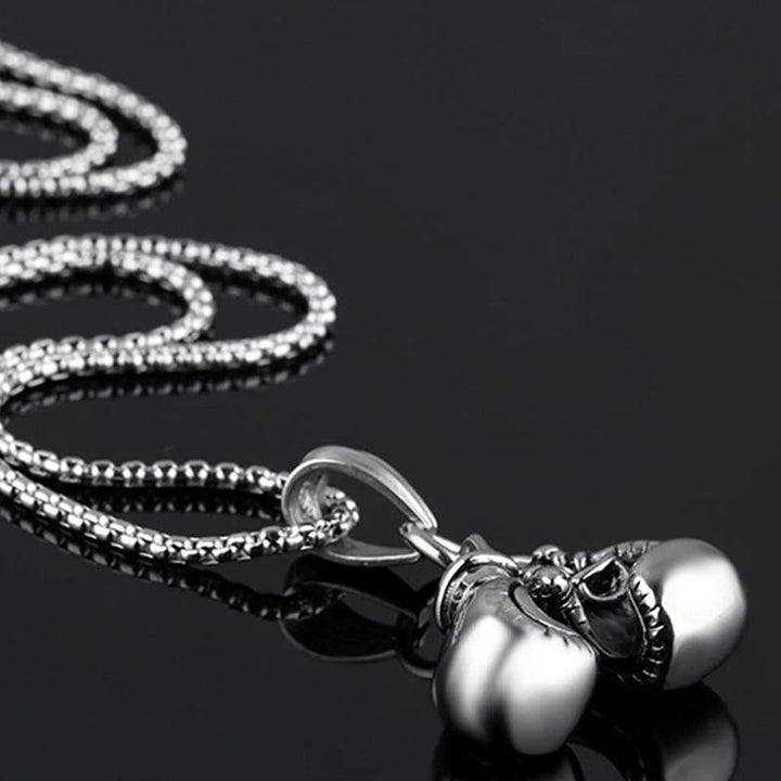 "Unisex boxhandskar halsband i ett glänsande guldigt titanstål, symboliserar styrka och stil för boxningsentusiaster."