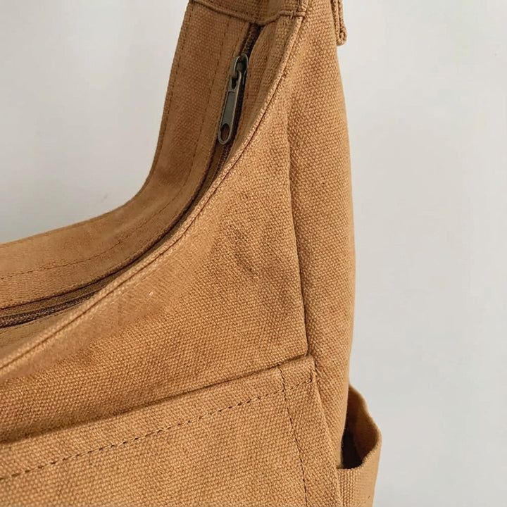Öppen canvas messenger väska visar organiseringsfack och innerfickor. Håller ordning på dina tillhörigheter.