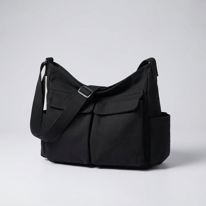 Praktisk canvas axelväska med justerbar rem, sedd från sidan. En idealisk unisex messenger väska.