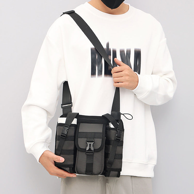 Unisex crossbody axelväska i tåligt tyg, grå. Framifrån med dragkedjor och justerbar rem, perfekt för organiserad förvaring.