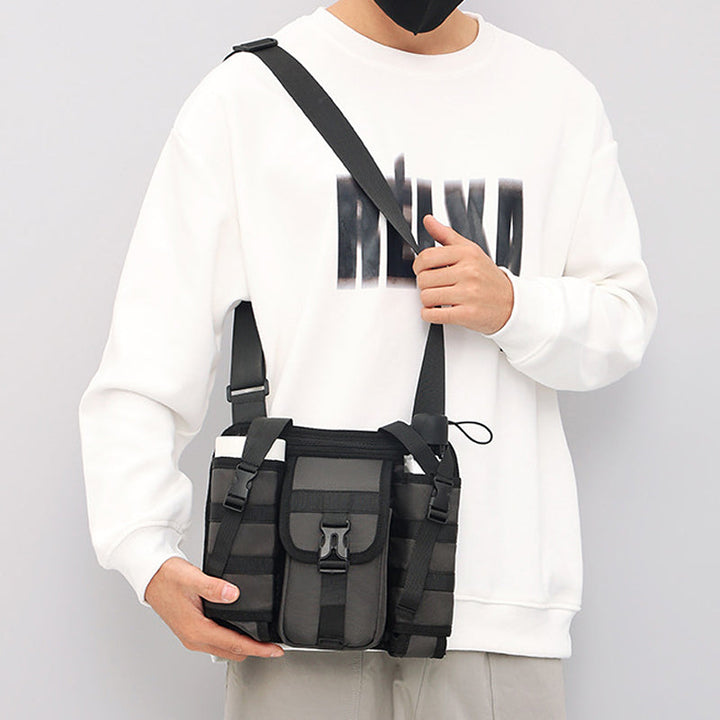 Unisex crossbody axelväska i tåligt tyg, grå. Framifrån med dragkedjor och justerbar rem, perfekt för organiserad förvaring.