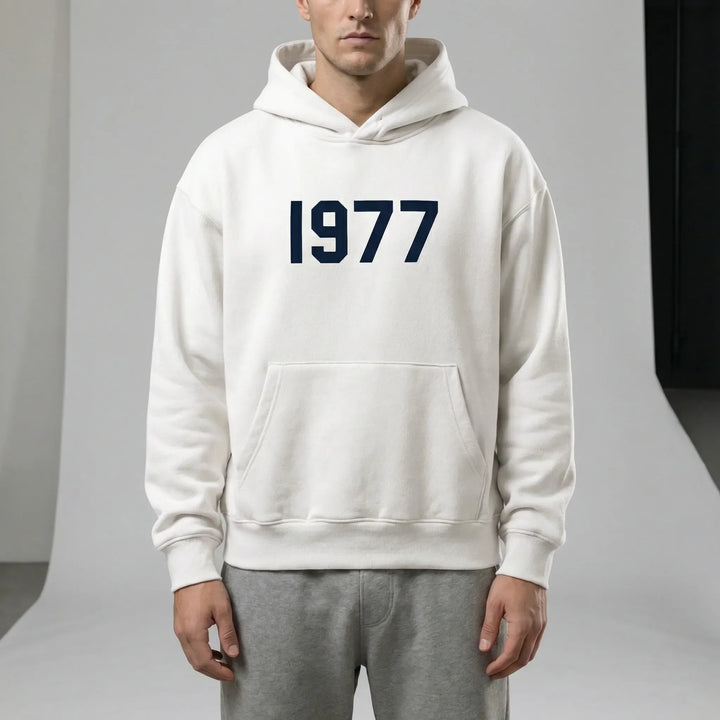 1977-tryckt retrotröja, en bekväm unisex hoodie med raglanärmar. Perfekt för avslappnat mode och fritid.