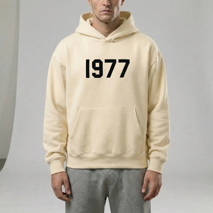 Modern unisex hoodie med raglanärmar och retro 1977-tryck. Ger unik streetwear-stil för alla.
