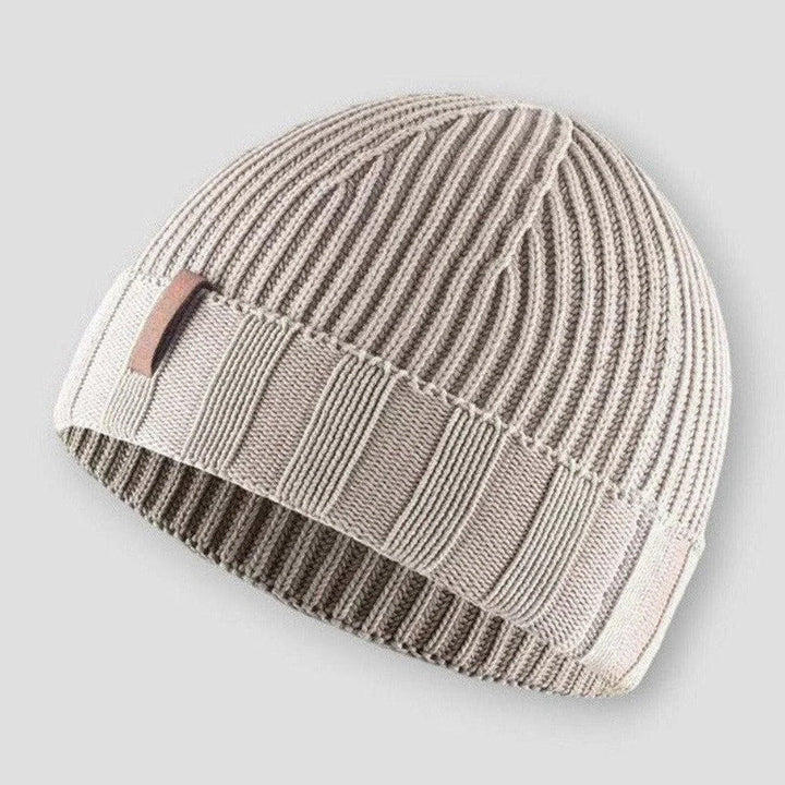 Närbild på en varm unisexmössa med trendig sliten look och vintage stickad design.