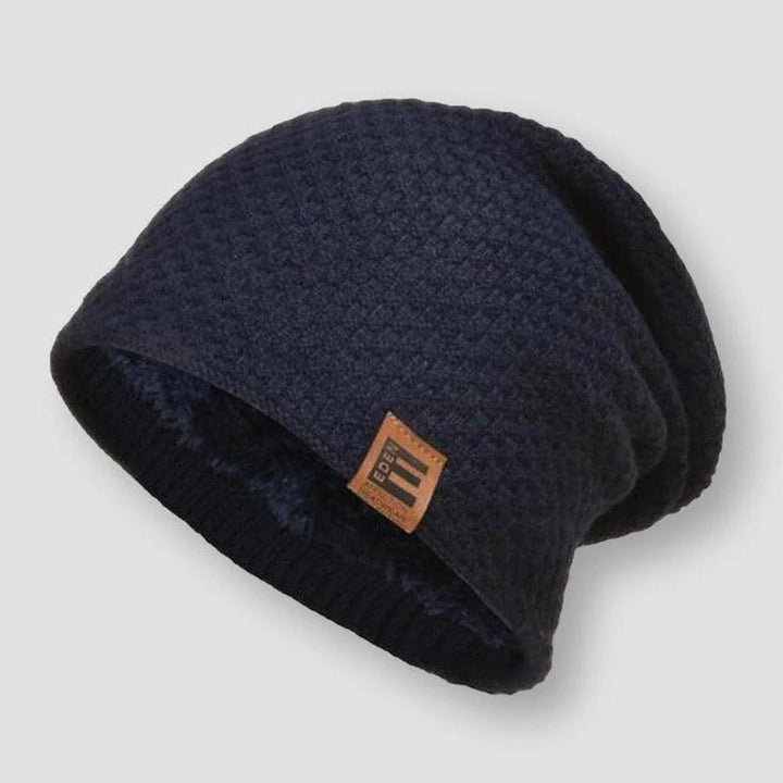 Modebild på en person som bär en beige våffelstickad beanie med fleece, passande för utekläder.