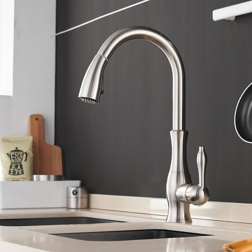 Modern utdragbar köksblandare monterad vid diskbänk i rostfritt stål, redo för användning.
