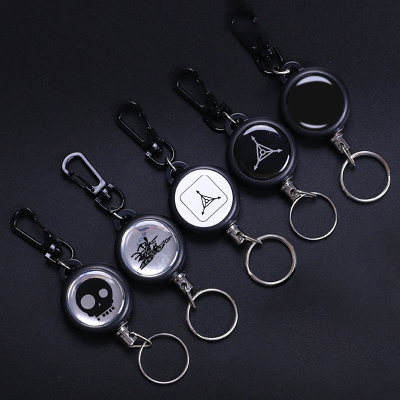 "Utdragbar nyckelring i metall med 60 cm stark stållina, perfekt för bälte eller ryggsäck. Slitstarkt och praktiskt tillbehör