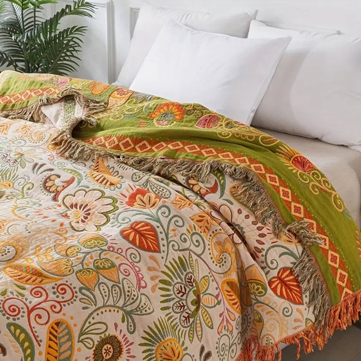 Mjuk bohemisk pläd med blommigt mönster. Vändbar design för mysiga stunder i hemmet.