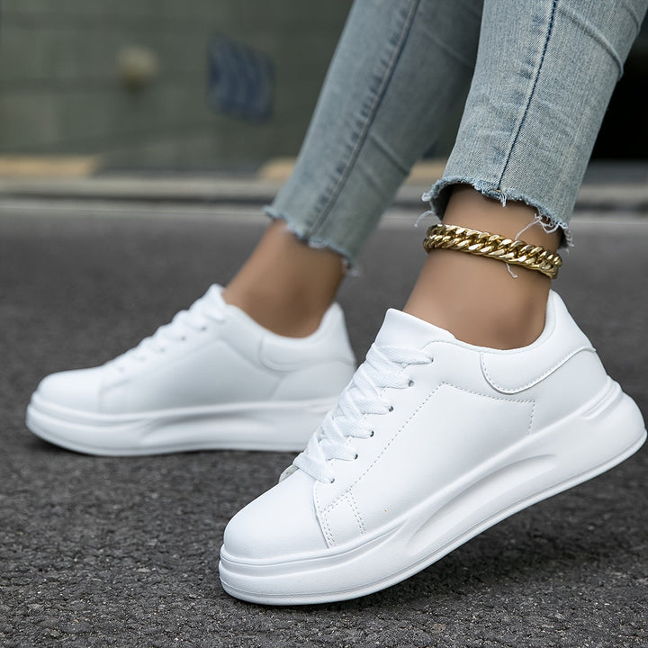 Vita ortopediska dam sneakers framifrån med vita snören. Stödjande vardagsskor med stil.