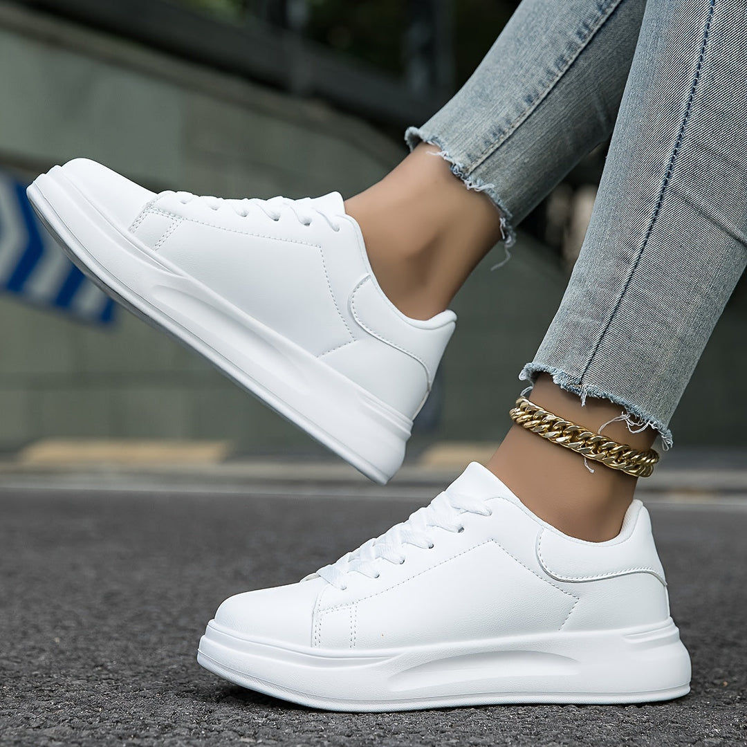 Dam bär vita ortopediska sneakers, perfekta för promenader. Bekväma och stödjande vardagsskor.