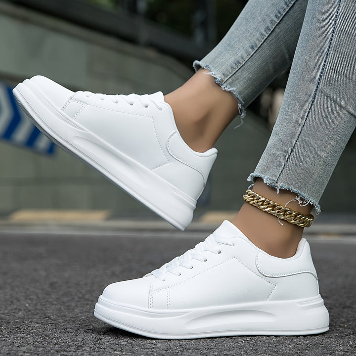 Dam bär vita ortopediska sneakers, perfekta för promenader. Bekväma och stödjande vardagsskor.