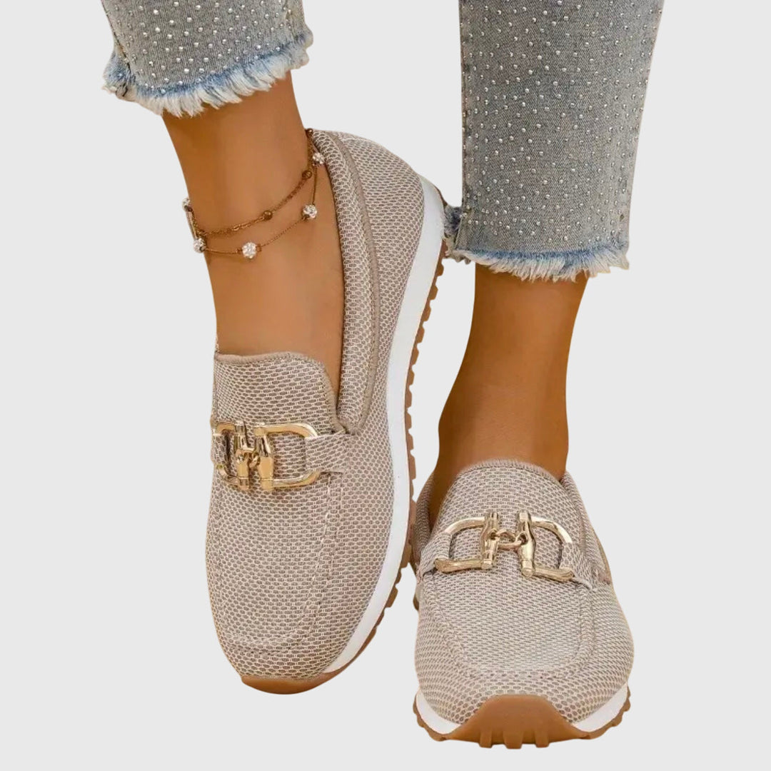 Kvinnors vita slip-ons på ett snyggt trägolv, redo för en avslappnad vårdag.