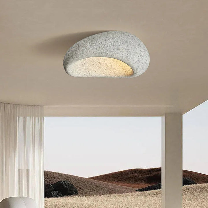 Mjuk belysning från minimalistisk wabi-sabi taklampa. Perfekt för mysig atmosfär i ett modernt hem.